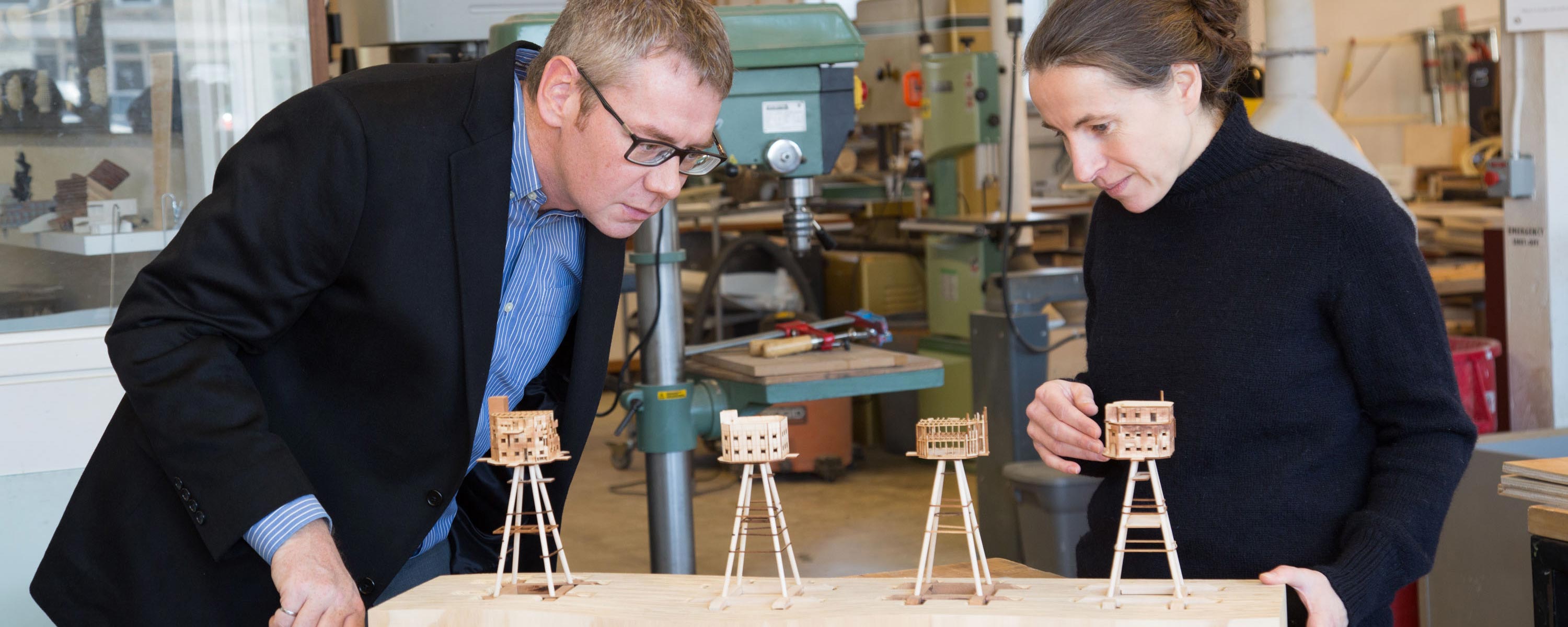Two-architects-looking-at-four-small-wood-models