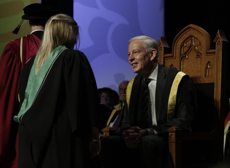 Dominic Barton congratulates a graduate.