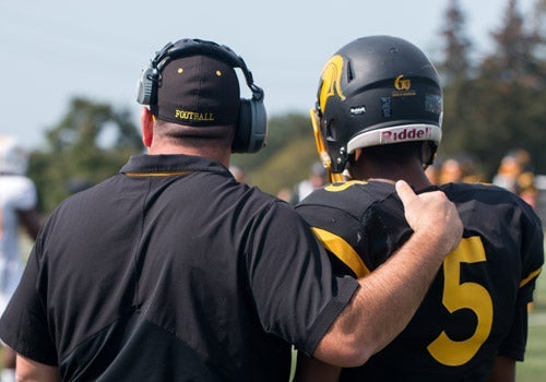 Chris Bertoia with his arm around Tre Ford looking out into field