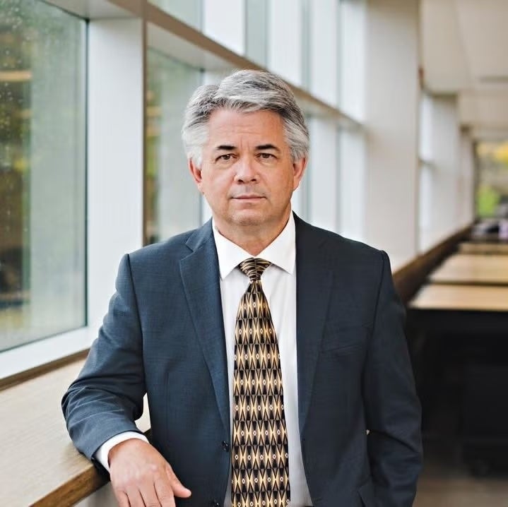 Blair Feltmate wears a suit and poses by a window.
