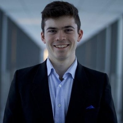 Image of a student in a suit smiling at the camera
