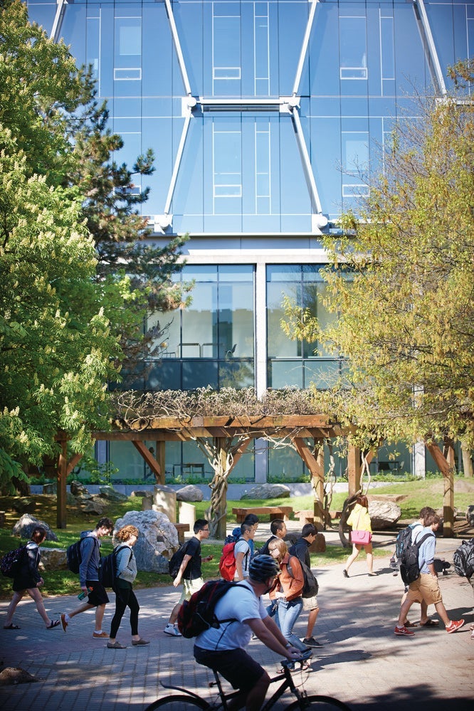 Students walk and bike to class on a footpath in front of the Quantum Nano Centre's distinctive honeycomb facade