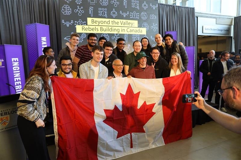 Toby and Vivek hold a Canadian flag with a group of student