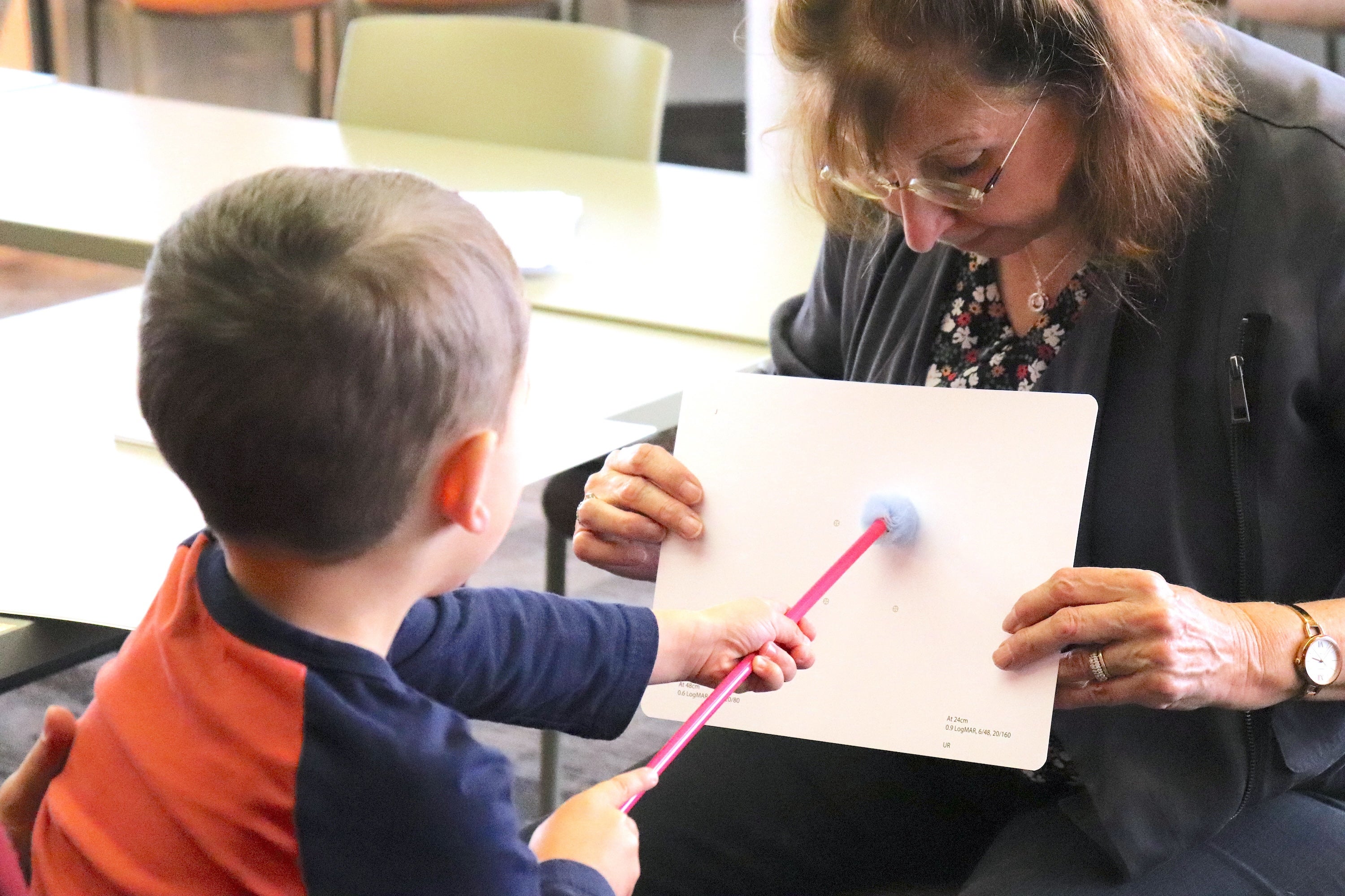 small child holding a pointer against a shape on a board
