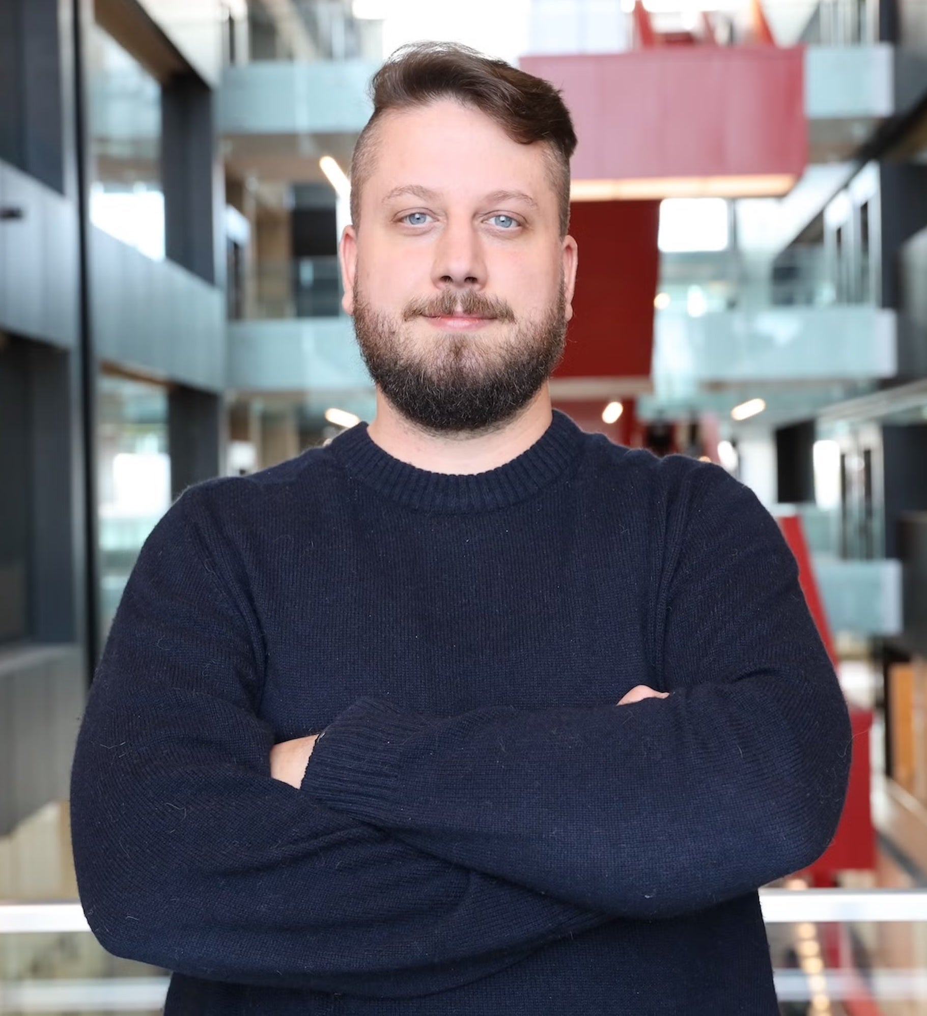Doctor Christian Euler standing with arms folded in a Waterloo Engineering Building
