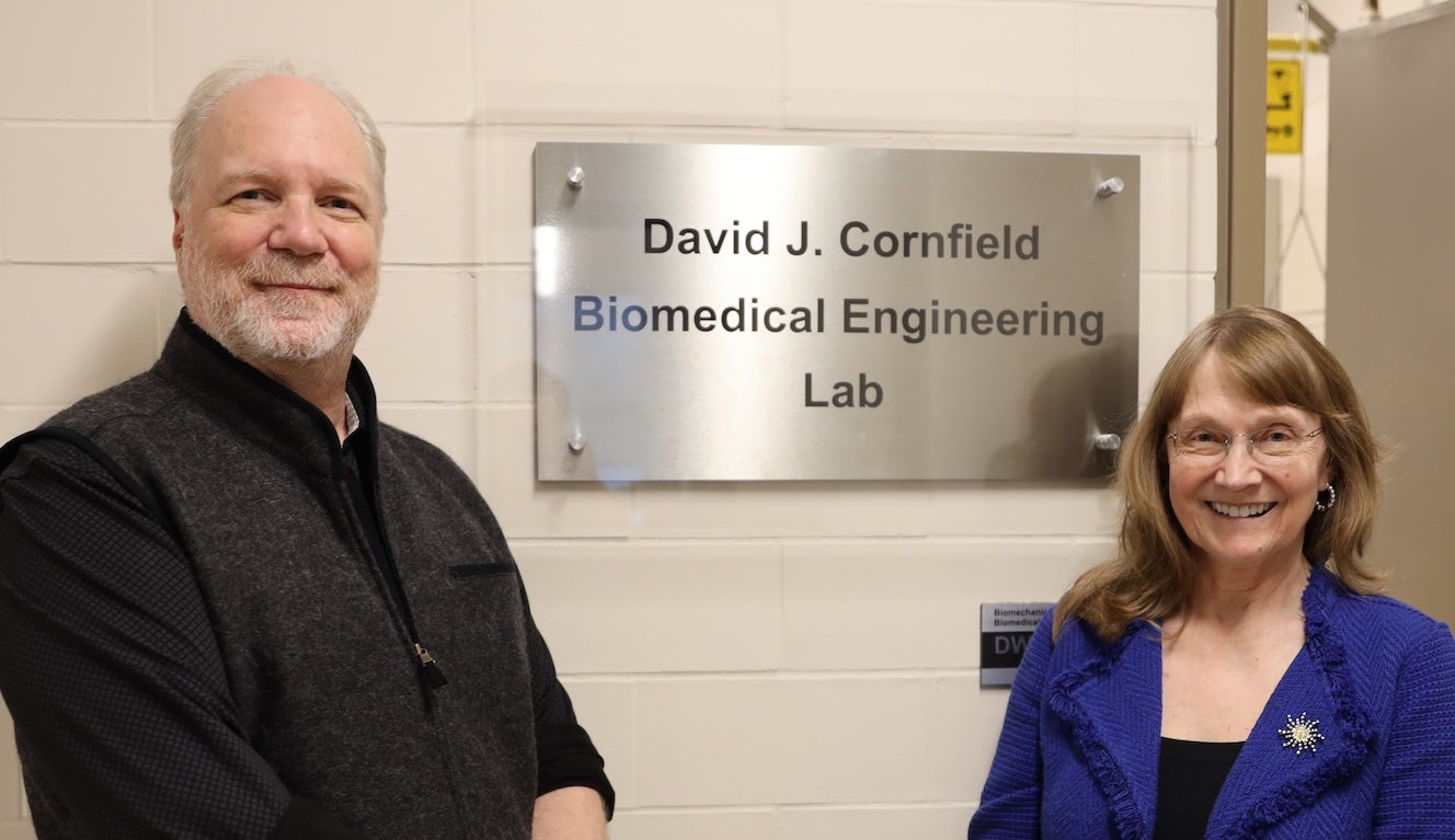 Two people next to a sign