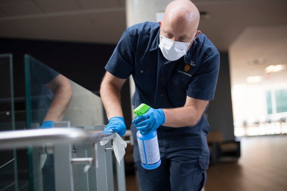 A member of the plant operations team disinfects a high-touch surface in the STC building