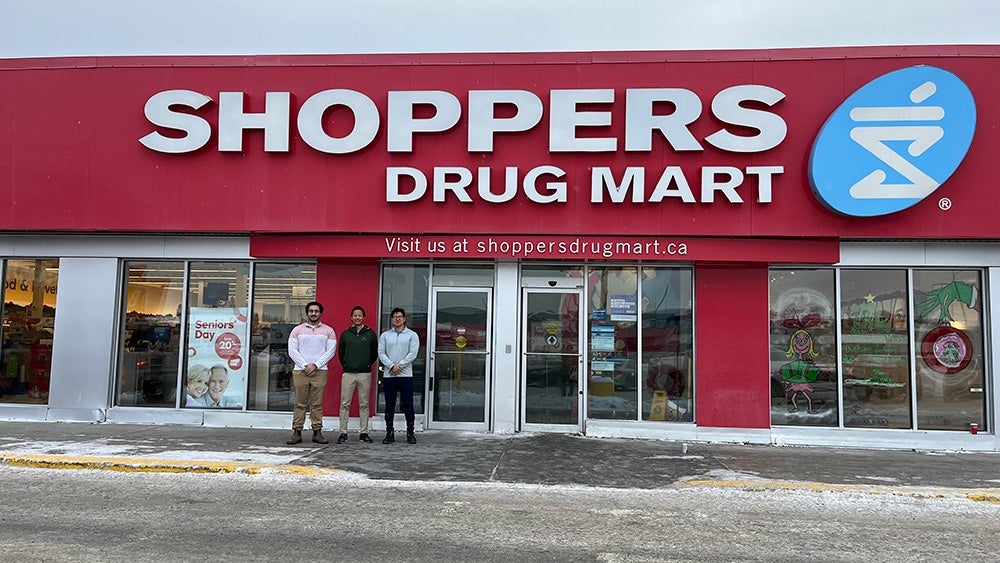 Three people standing in front of Shoppers Drug Mart