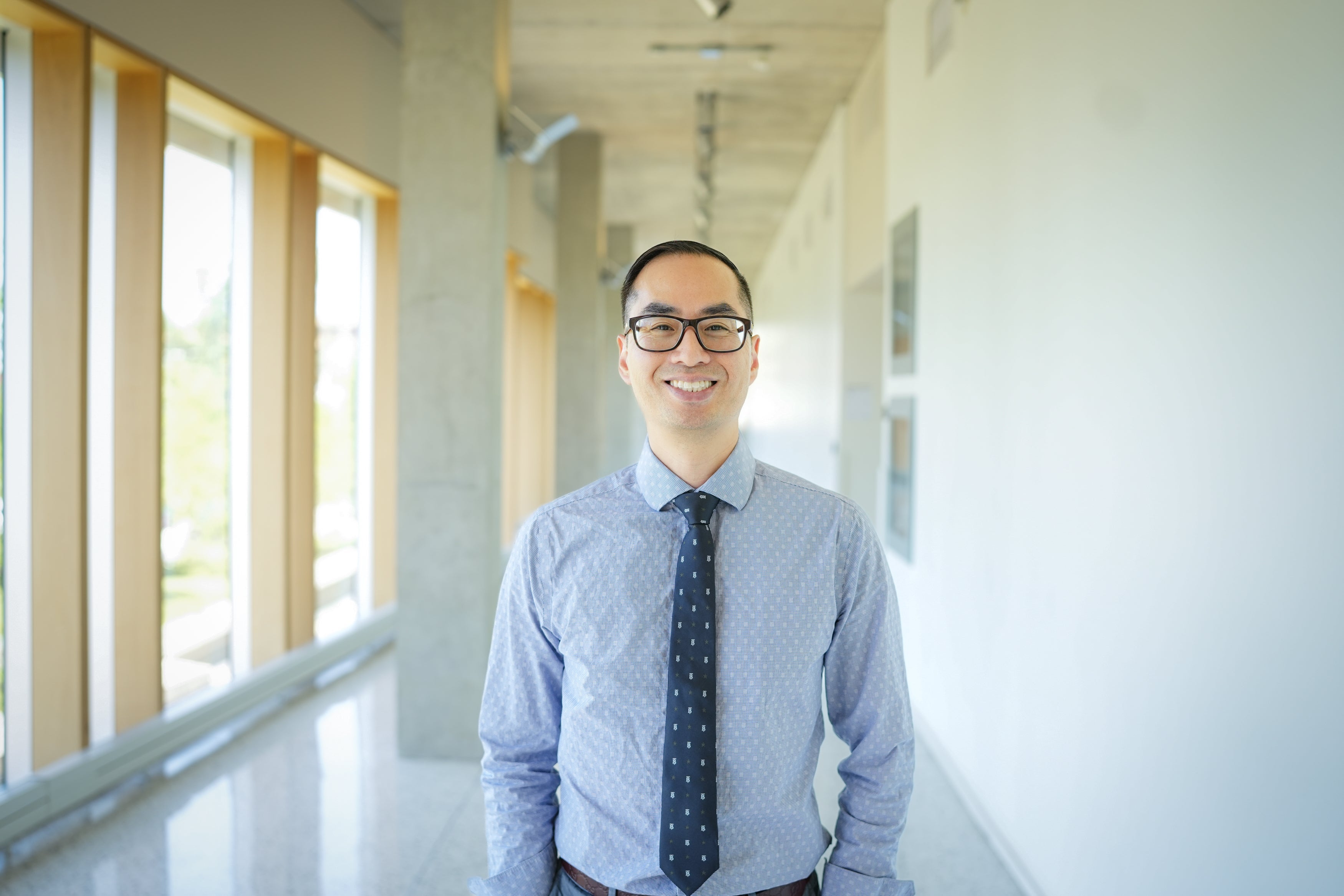 Dr. Emmanuel Ho standing in a hallway with windows