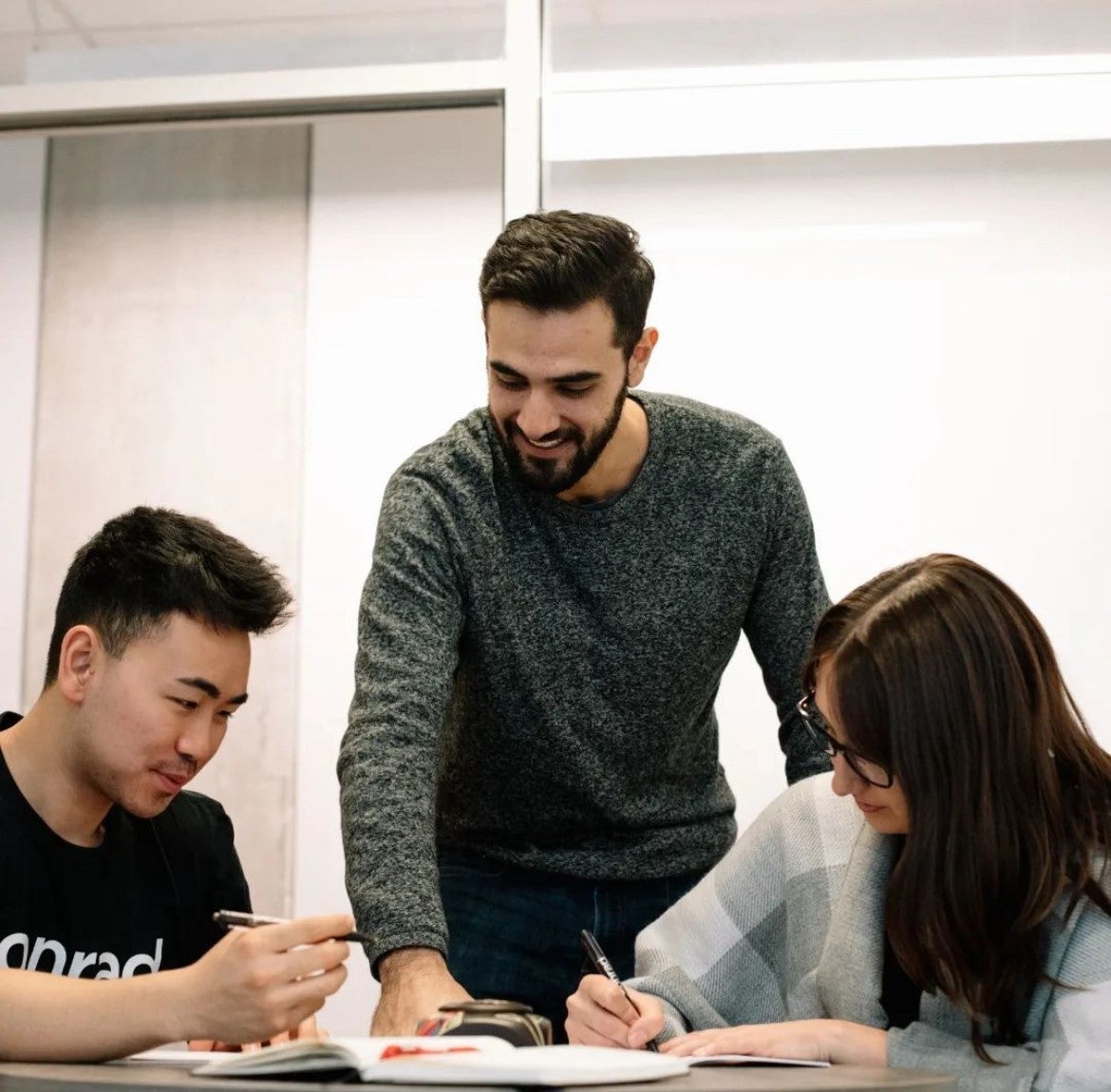 Esteban Veintimilla stands while two students take notes in books