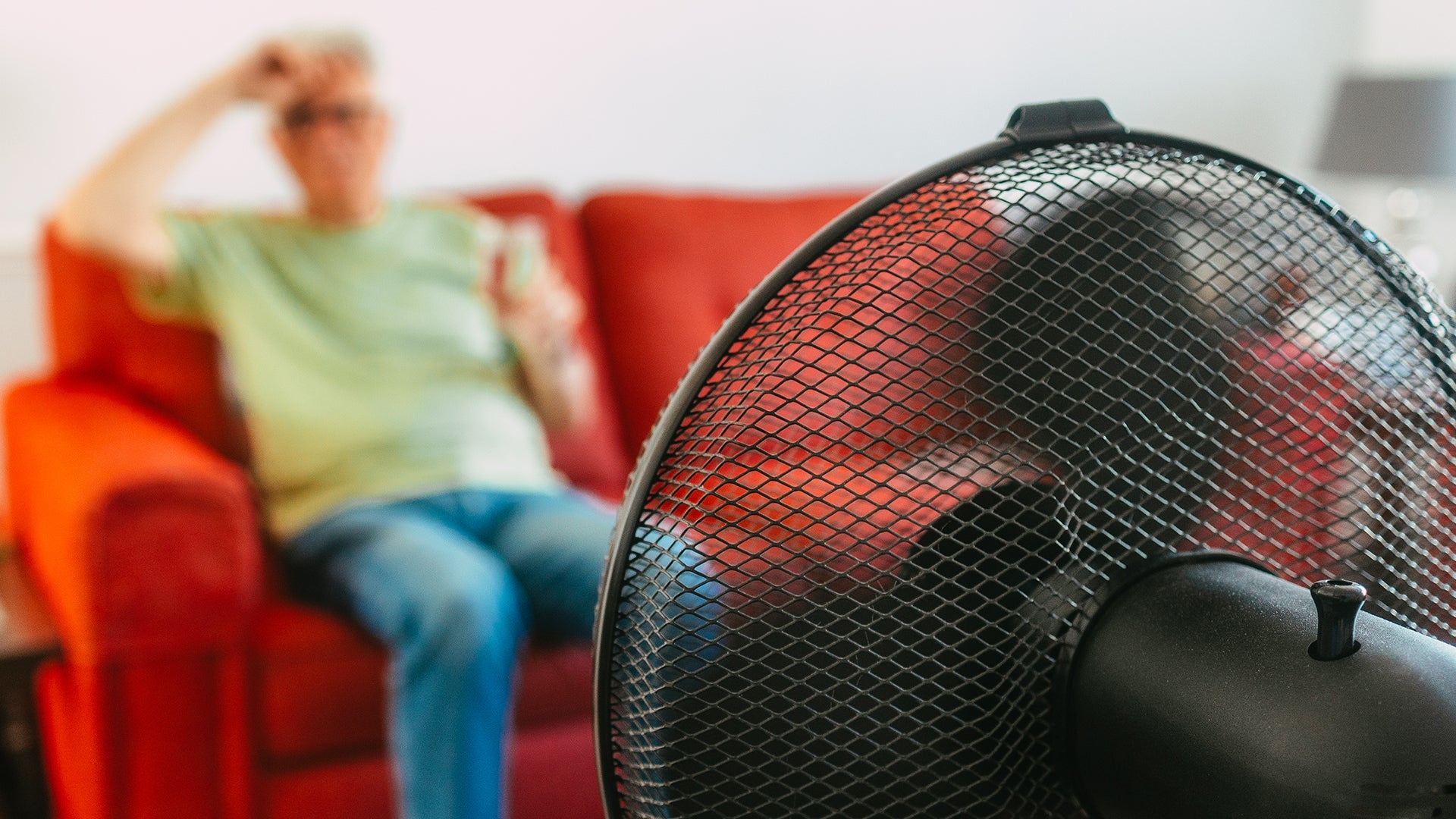 Person sits on couch with fan pointed at them