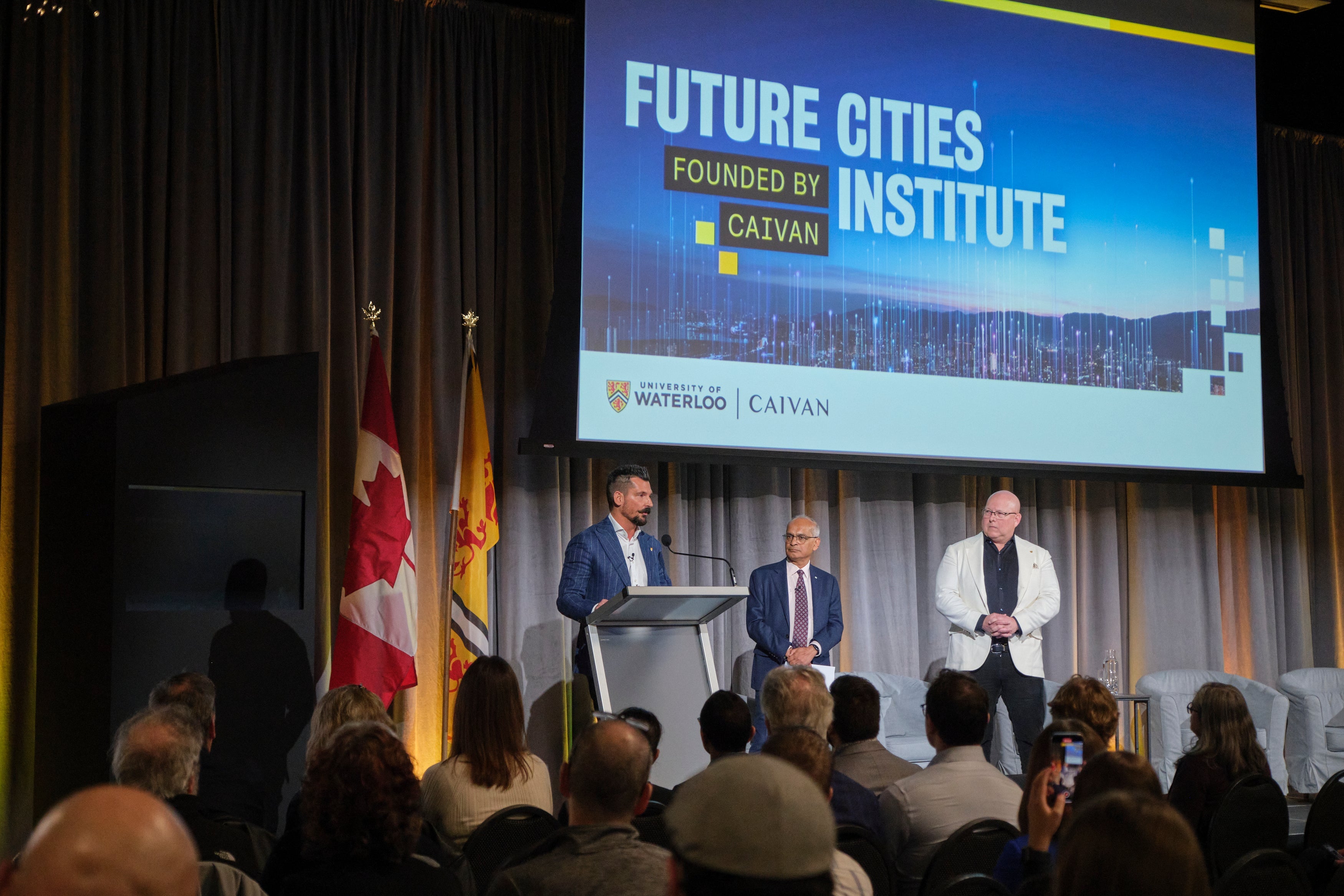 Frank Caivan (left), Vivek Goel (centre), Troy van Haastrecht (right) standing on stage during launch of Future Cities Institute
