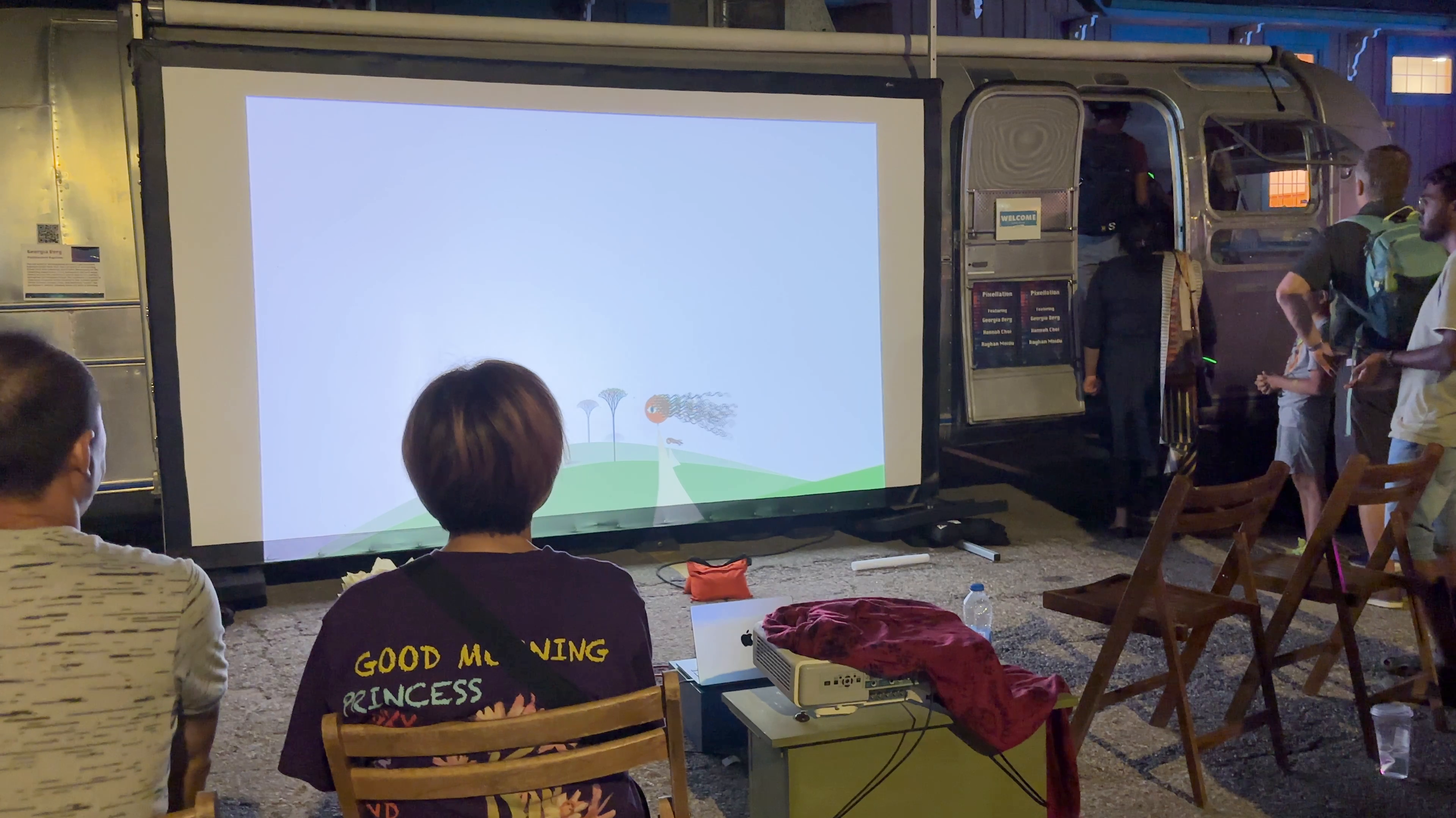 People standing outside a bus watching a piece of art on a projected screen