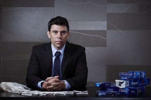 Professor David Hammond, seated at desk with packages of cigarettes