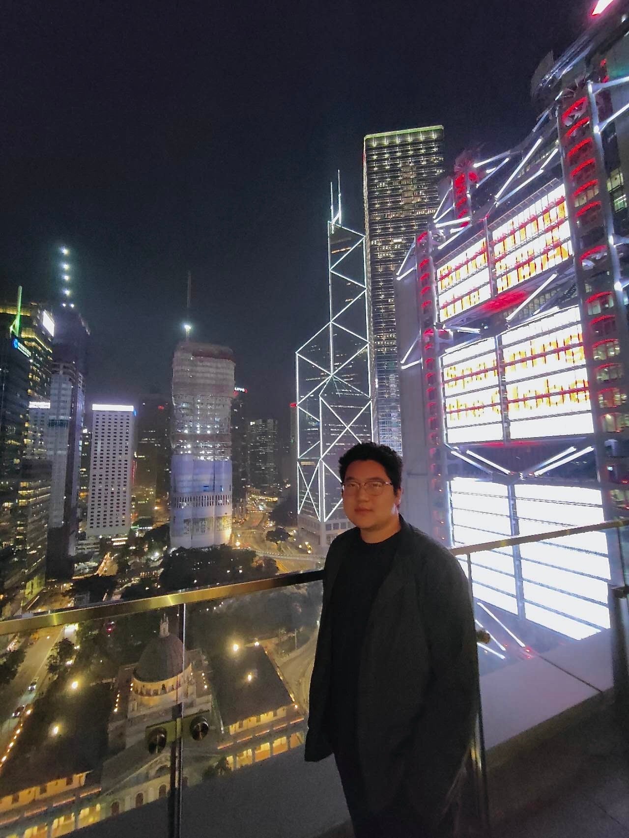 Jeremy Zhu stands in front of the Hong Kong skyline