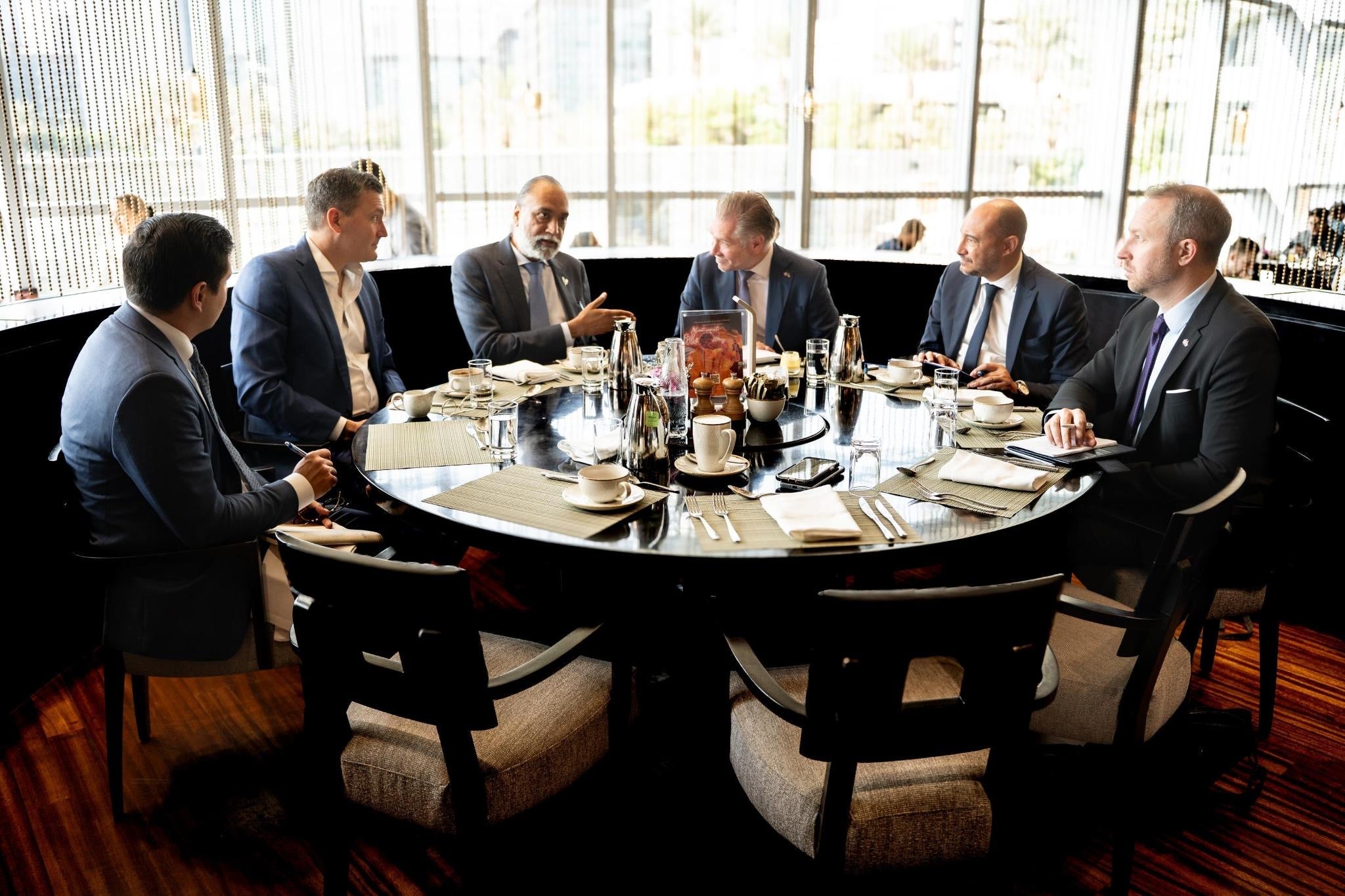 Group of men including Mark Schaan and Evan Solomon are seated at a table in conversation