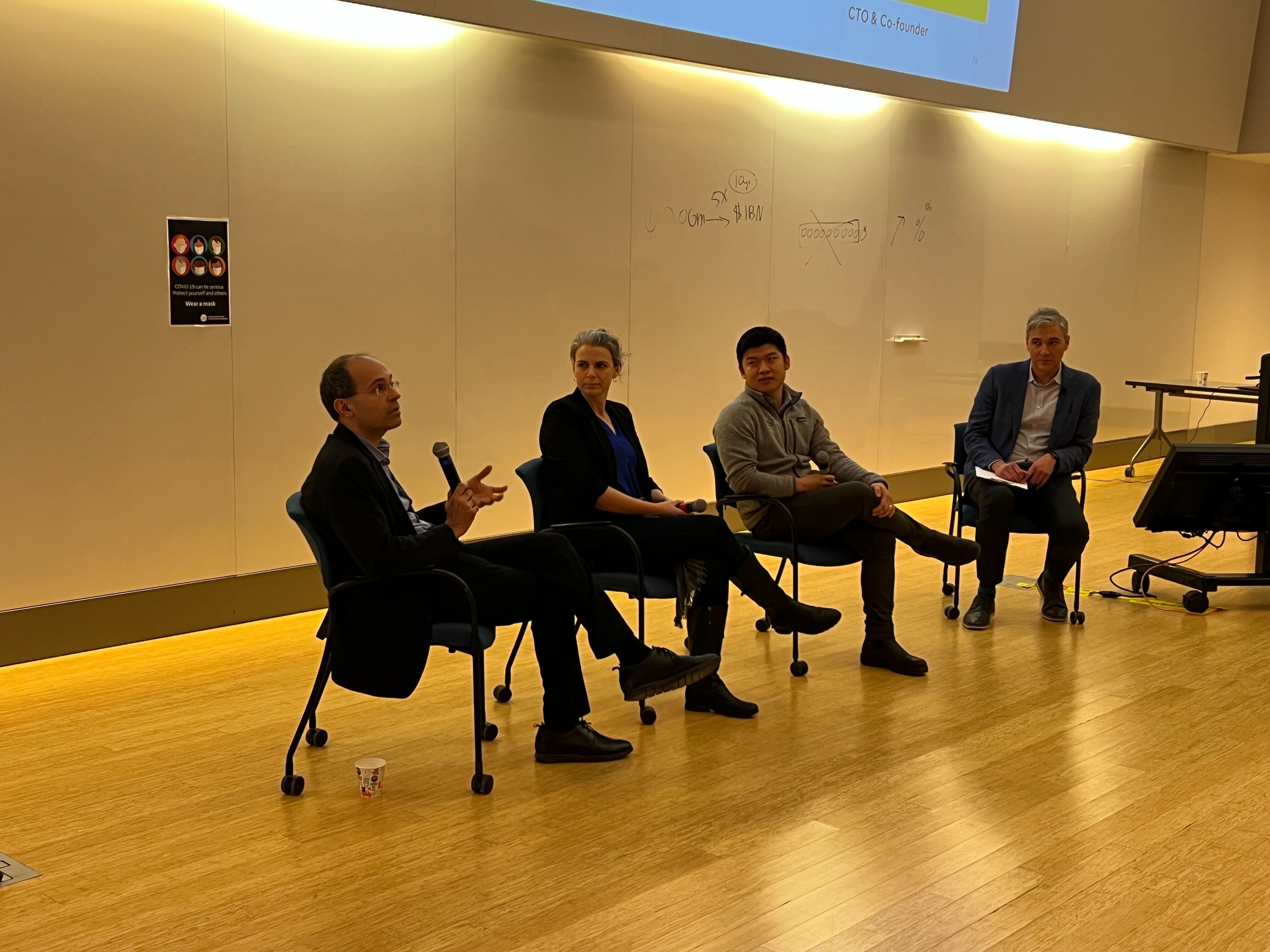 Four panelists at the Velocity event sitting on chairs at front of lecture theatre