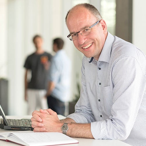 Norbert Lutkenhaus leaning on a table with his computer