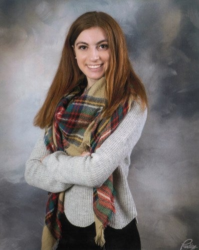 A young woman dressed in a scarf with a big bright smile
