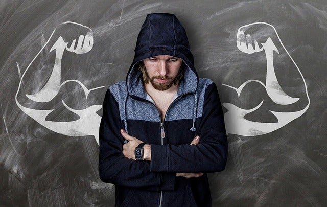 Man standing next to wall with muscular arms on either side of him.