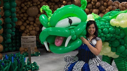 Girl with balloon dragon wearing a dress made of balloons 