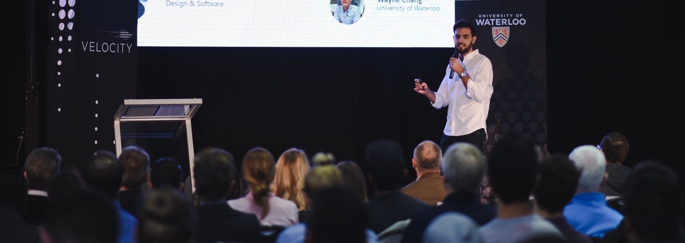 Esteban Veintimilla stands on conference stage holding a microphone as he give presentation