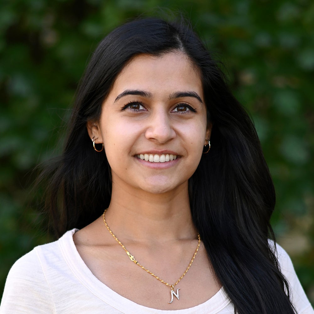 Nikhita Joshi smiling while standing in front of a living wall