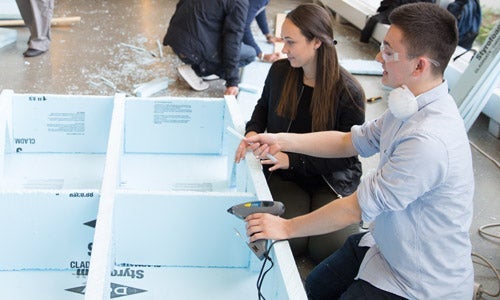 Engineering students working on building a Styrofoam bridge