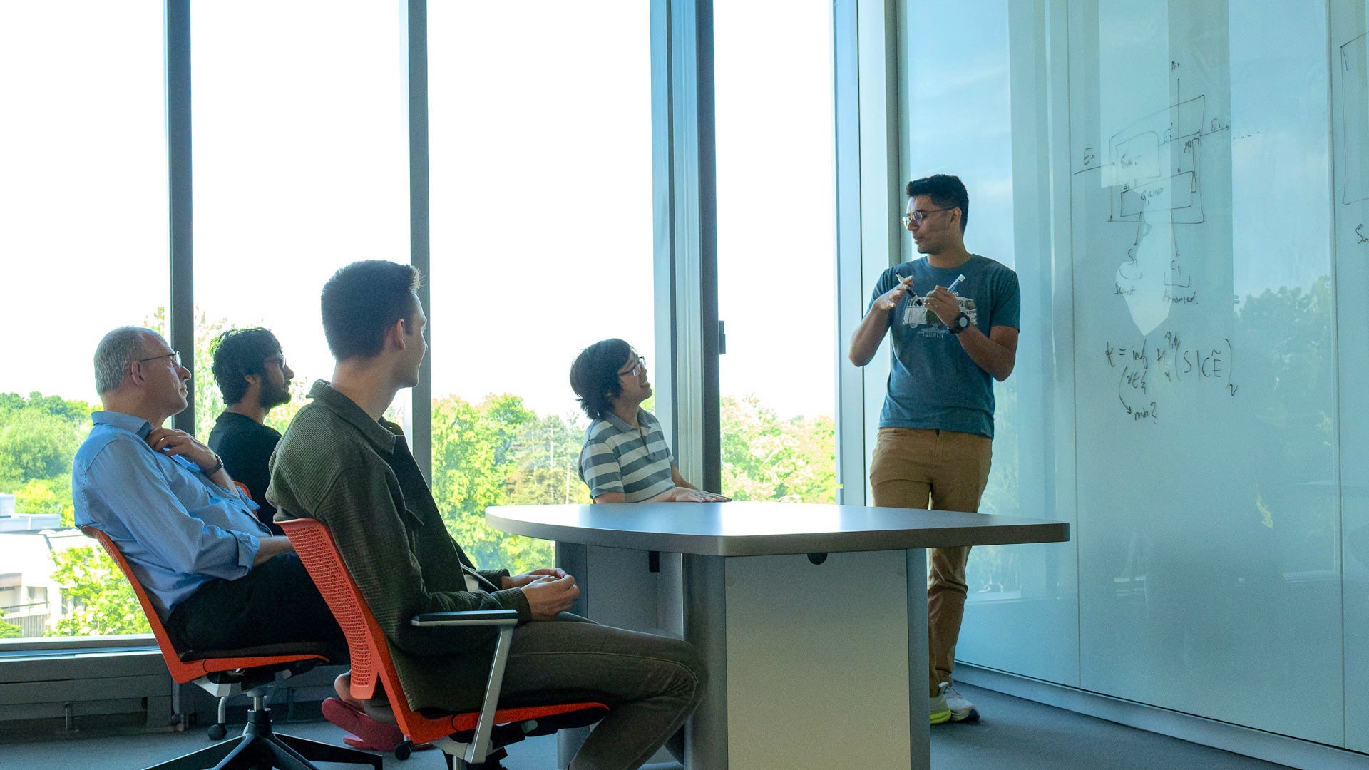 Dr. Norbert Lütkenhaus and group of PhD students and researchers discussing in a classroom