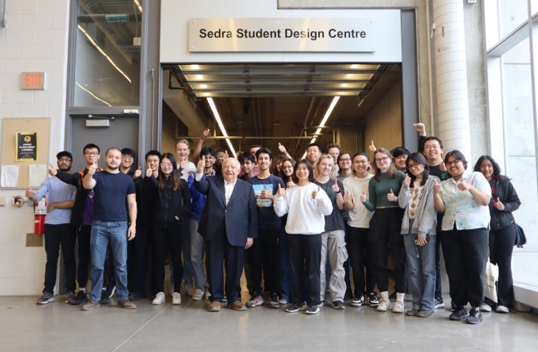 Adel Sedra standing with a group of students doing thumbs up in front of the Sedra Student Design Centre