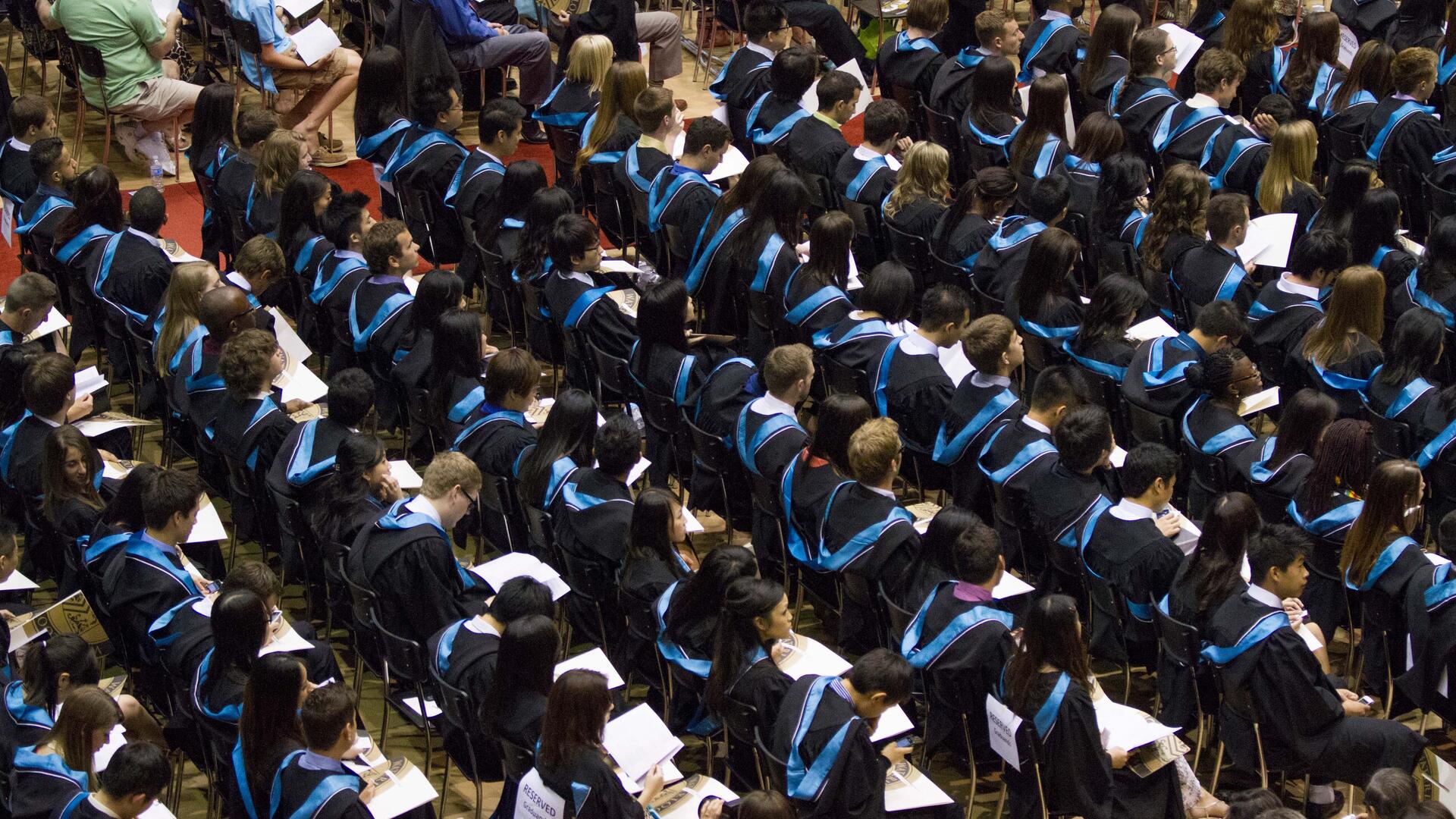 students sitting in the audience wearing convication gowns