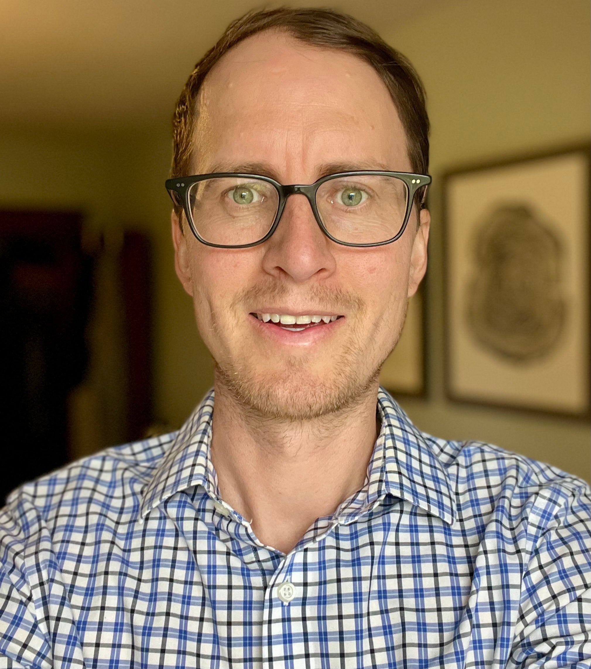 Stephen Smith wearing blue and white plaid shirt with dark framed glassed
