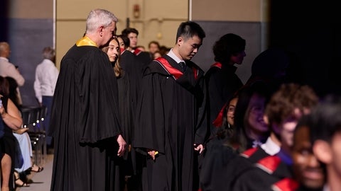 Marshall guides graduates into their rows during a convocation ceremony