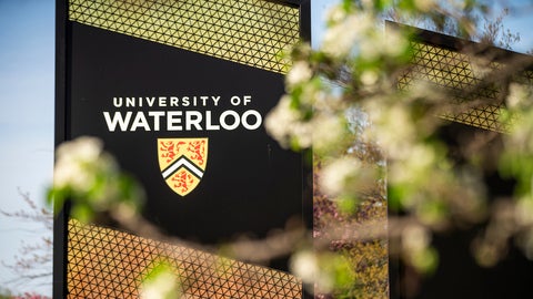 A close up photo of the UW sign with a blurred tree branch in the foreground