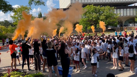 Orange smoke is released around a group of first year students