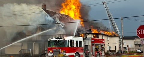 Fire fighters responding to fire in a large building engulfed in flames