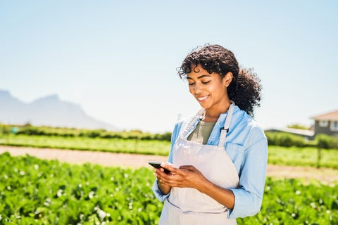 Woman wearing an apron using mobile device in a remote farm area