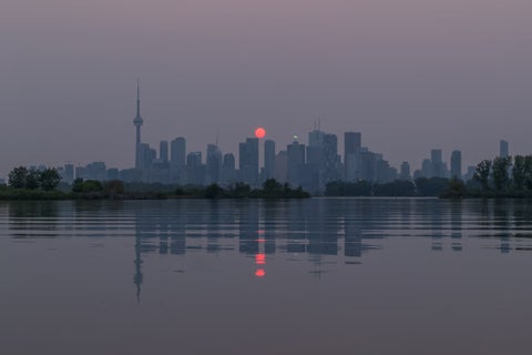Red sunset over Toronto's skyline caused by wildfire pollution.