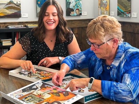 Olivia Vento and grandmother putting together PIece of Mind Cats Having Breakfast puzzle activity