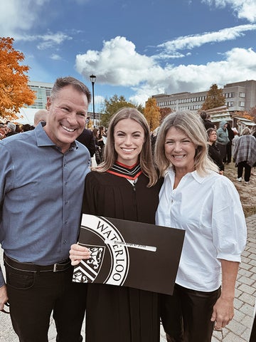 Kristin O'Neill poses for a photo with her parents at convocation, proudly holding up her diploma