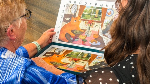 Olivia Vento and her grandmother looking at the interior of the Piece of Mind Cats Having Breakfast puzzle box