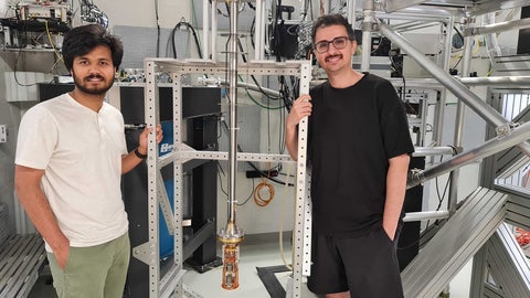Sahand Tabatabaei and Pritam Priyadarsi stand next to a large microscope