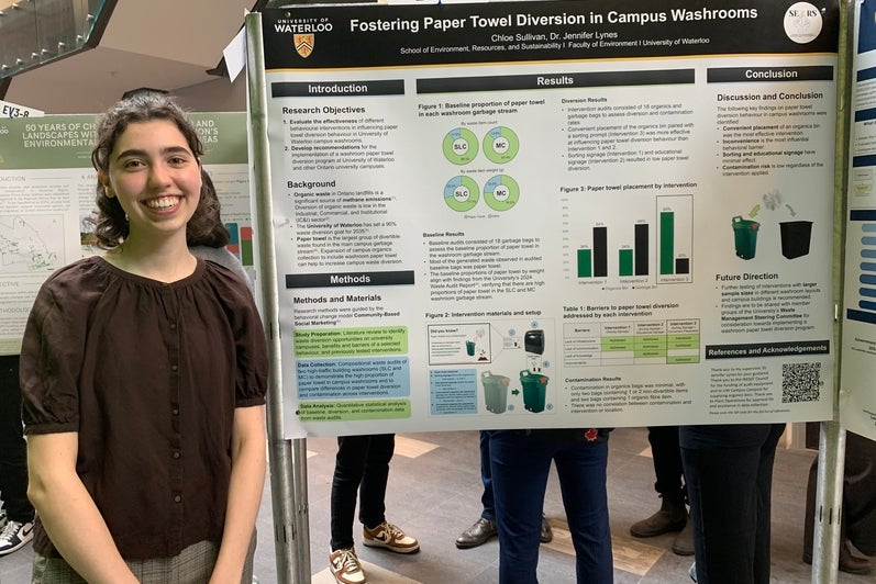 Chloe Sullivan standing beside her Capstone Symposium poster presentation
