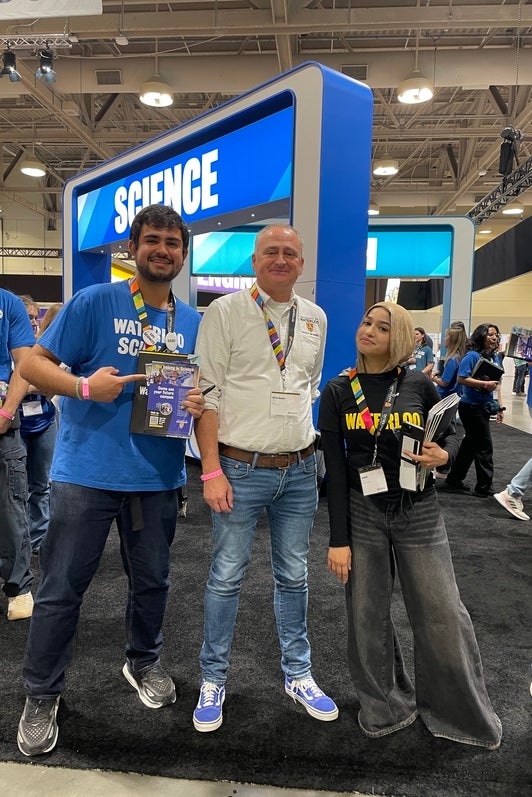Ayush Verma with Chris House and another Waterloo student posing at the Ontario Universities Fair with Faculty of Science sign in the background