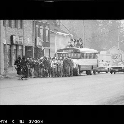 Black and white photo of students pulling a school bus