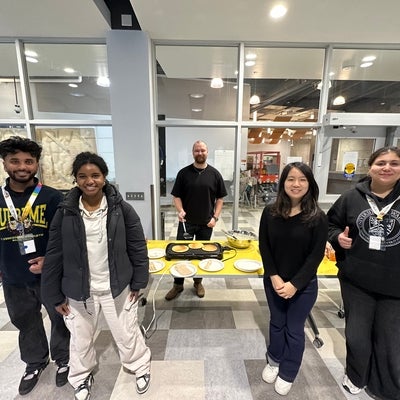 Luke Manimendre and four friends standing in front of pancake event at Claudette Millar Hall
