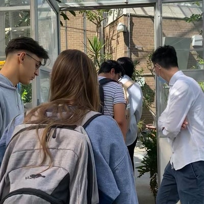 Participants in the Real Research program are seen walking through the green house on campus