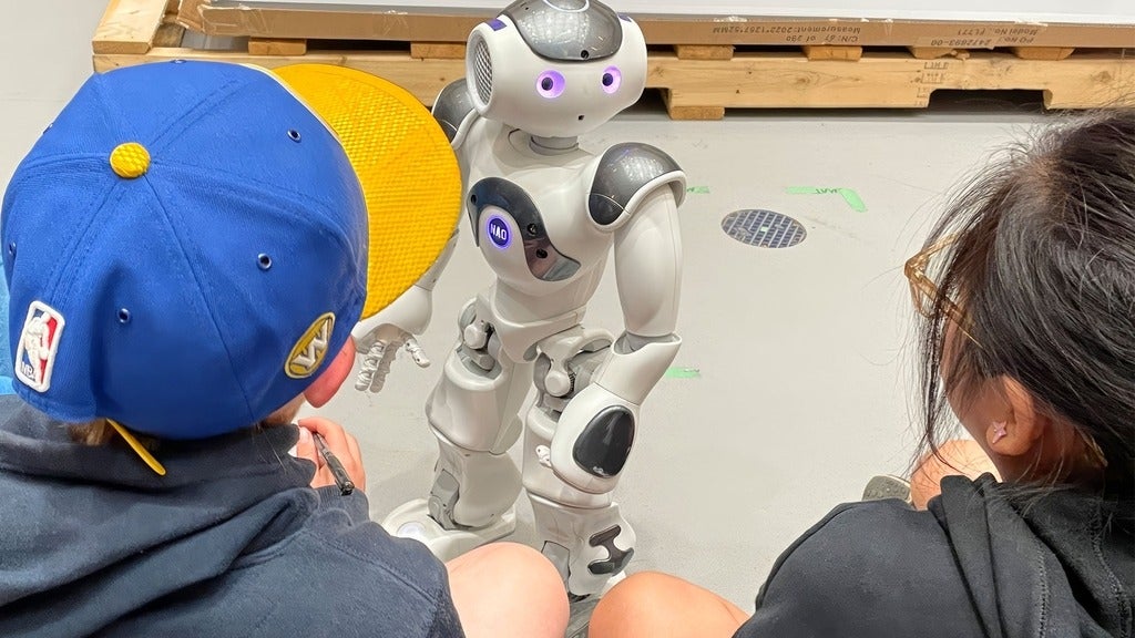 Two children interact with a robot