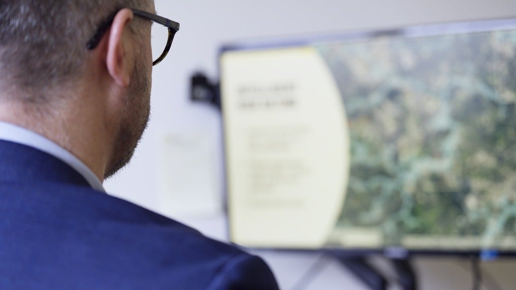 Over the shoulder of professor looking at a flood map on their computer screen