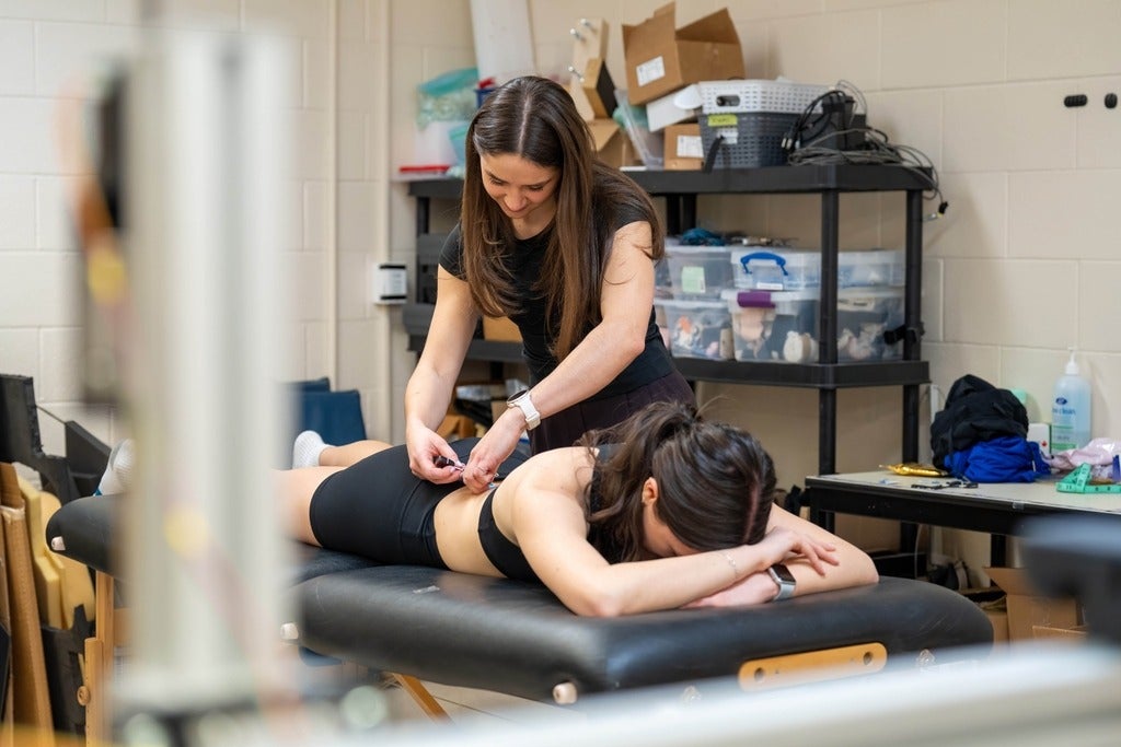 Juliana Bossom adjusts sensors on a participant's back